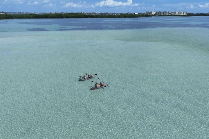 Zwei Kajaks gleiten durch klares, flaches Küstenwasser nahe dem Ufer