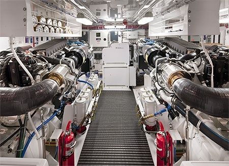 Zwei große Schiffsdieselmotoren in einem hellen, technischen Maschinenraum